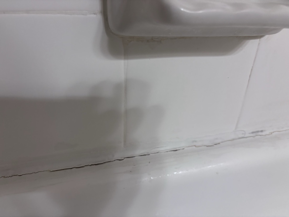 Stained, cracked tub caulk cleaned out and replaced: before