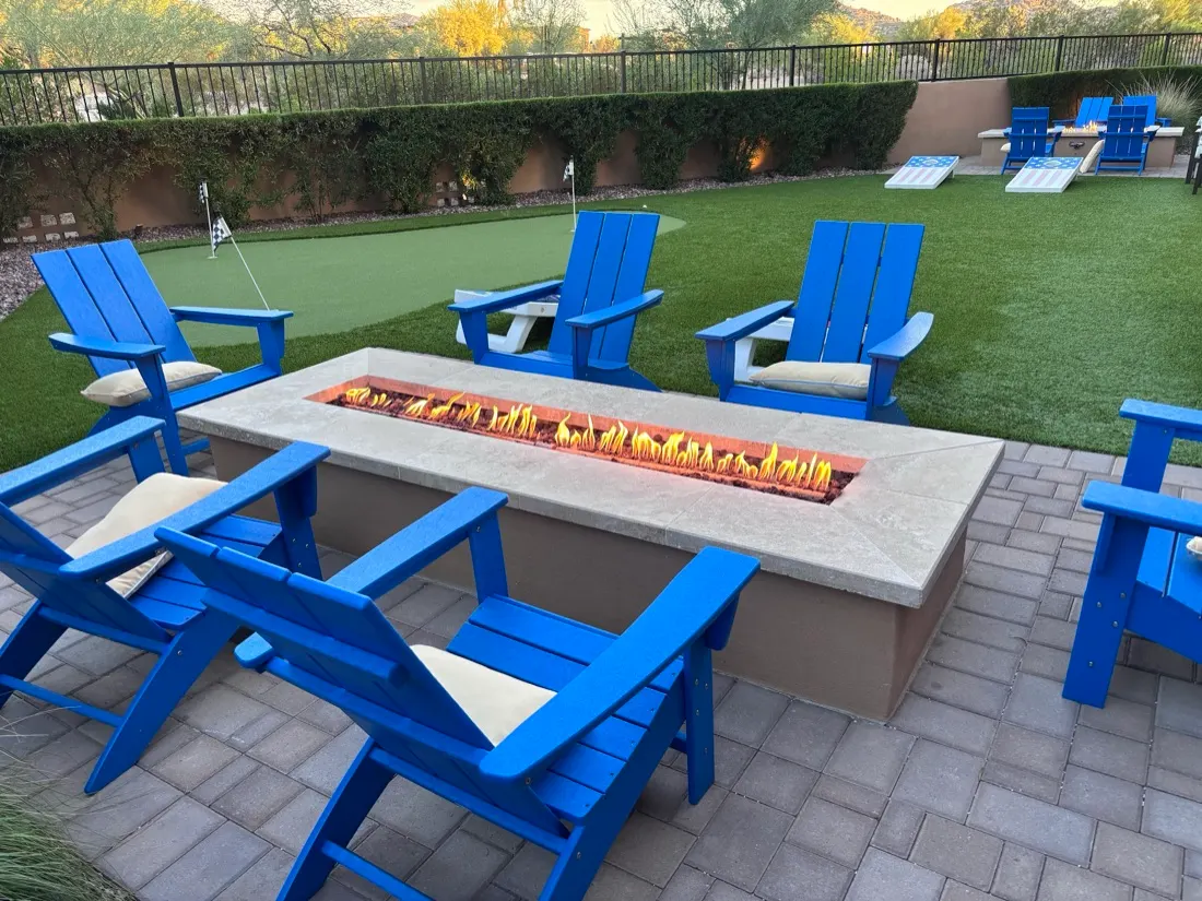 Blue Adirondack chairs around a backyard fire pit