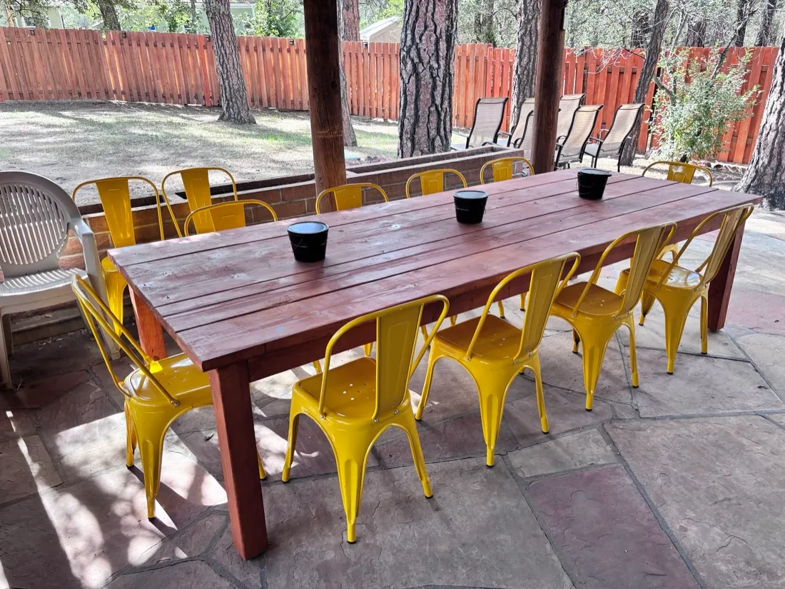 Yellow metal dining chairs around a long patio farm table