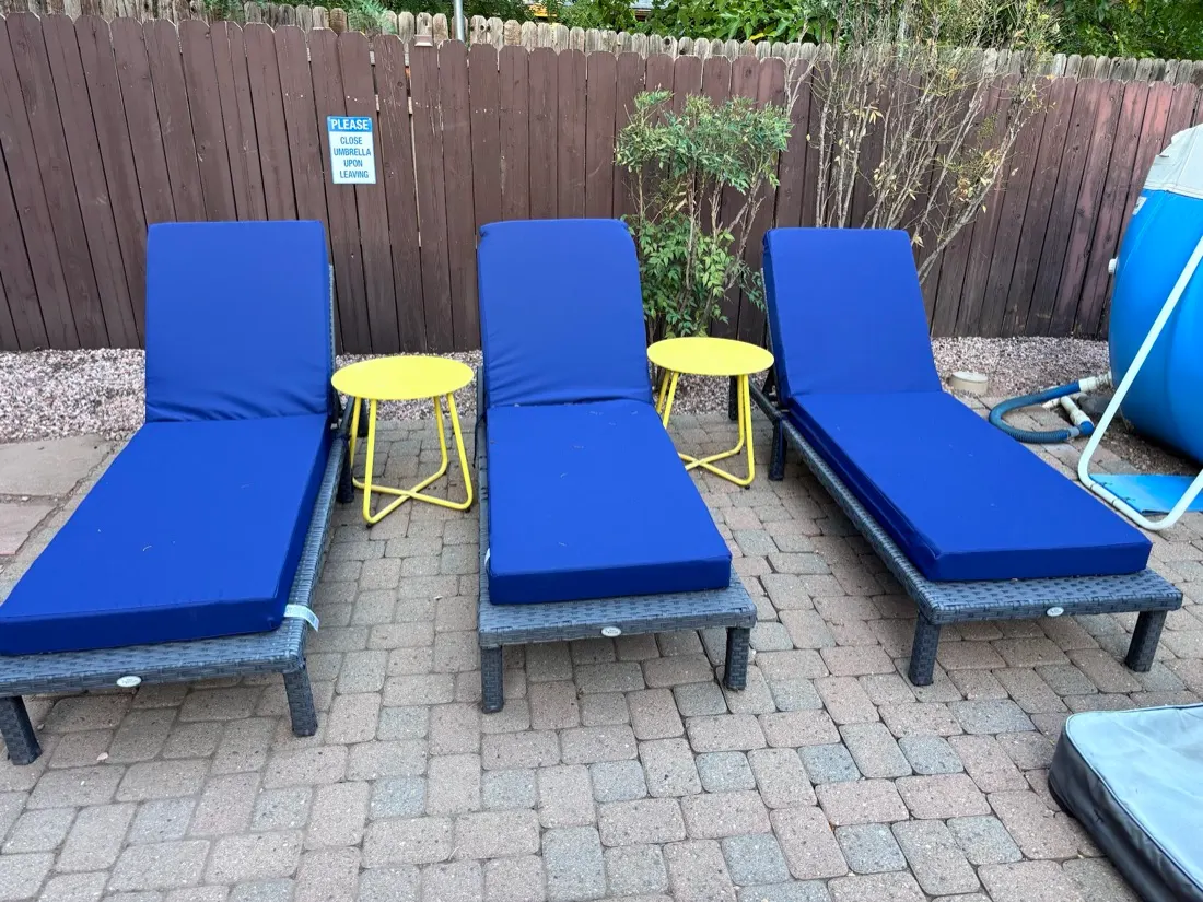 Wicker pool loungers with cushions and side tables