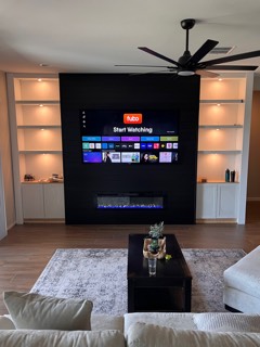 Black shiplap fireplace wall with a TV and lit built-in shelves on both sides