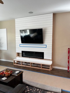 White shiplap TV and fireplace wall during the build, with the framing still visible