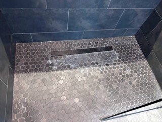Hard water and calcium buildup on a hex tile shower floor, before cleaning