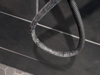 Calcium buildup on a black shower hose, before cleaning