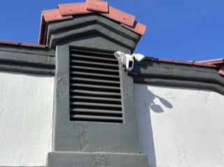 Floodlight security camera installed on a stucco wall