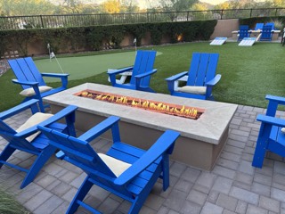 Blue Adirondack chairs around a backyard fire pit