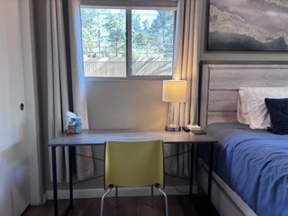 Writing desk and lamp set up by a bedroom window