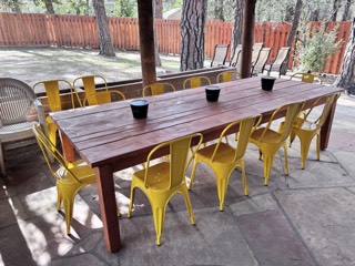 Yellow metal dining chairs around a long patio farm table