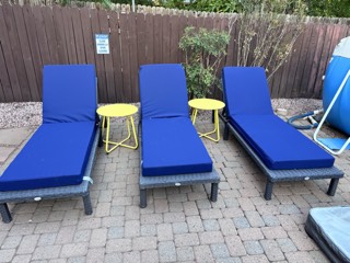 Wicker pool loungers with cushions and side tables