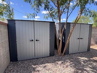 Two resin storage sheds assembled in a backyard