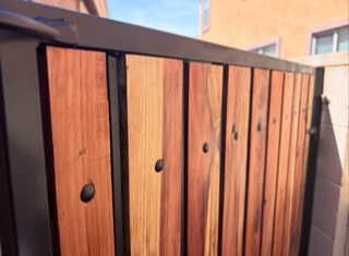 Close-up of redwood slats and black hardware on a refurbished gate