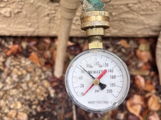 Checking household water pressure with a gauge on a hose bib