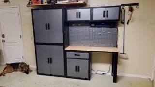 Garage storage cabinets, pegboard and workbench installed along a garage wall