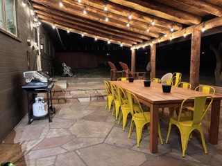 Bistro lights along the beams of a covered patio over an outdoor dining table