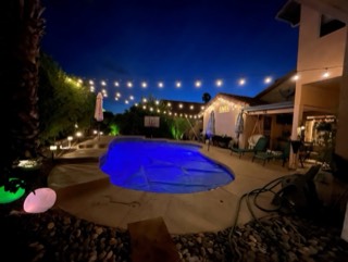 String lights crisscrossing a backyard pool and patio at night