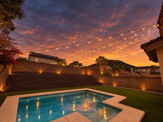 Bistro string lights on tension wire over a backyard pool at sunset