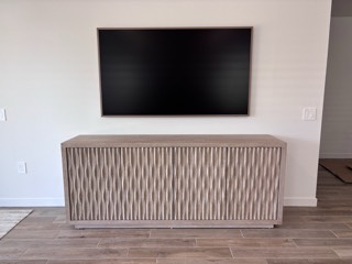 Samsung Frame TV mounted flush above a wood credenza
