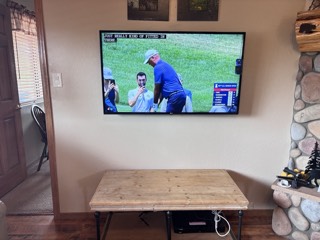 Flat-mounted TV on a living room wall beside a river rock fireplace