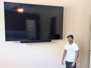 Large TV and soundbar mounted on a bedroom wall