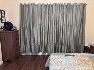 Sage green blackout grommet curtains across a bedroom window