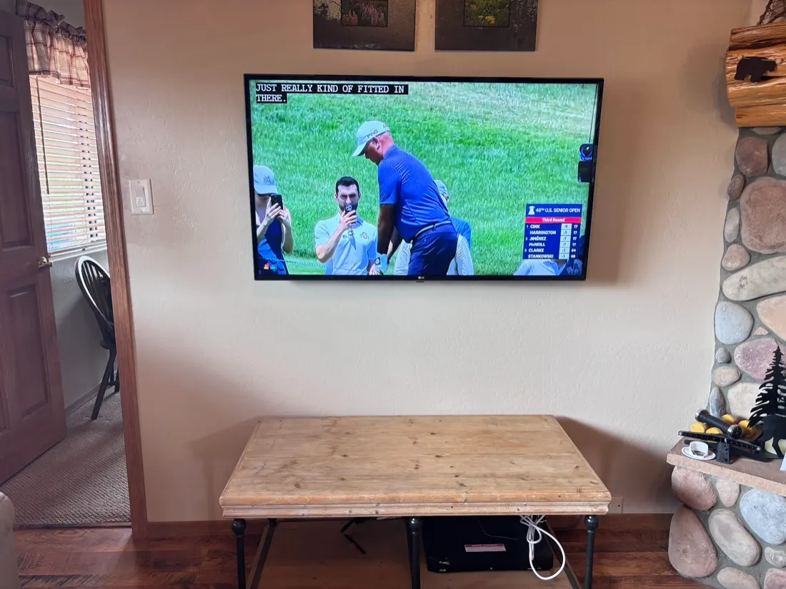 Flat-mounted TV on a living room wall beside a river rock fireplace