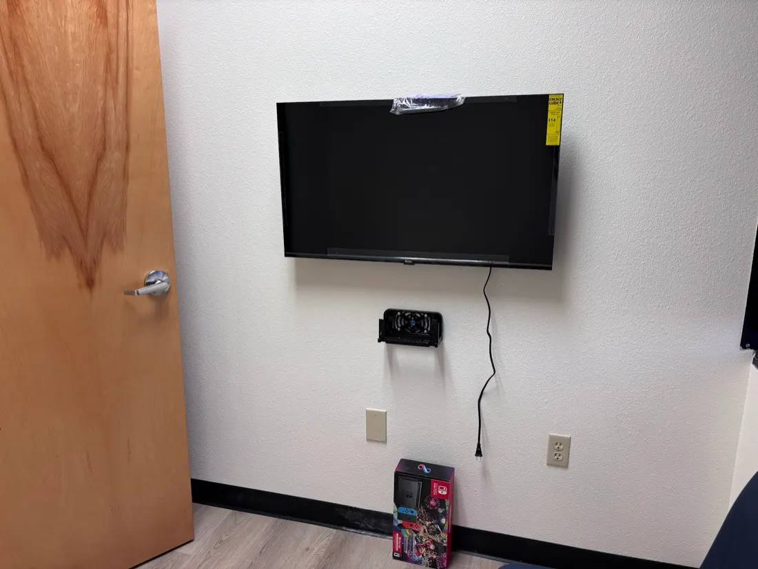 Office TV mounted with a wall shelf for a game console below