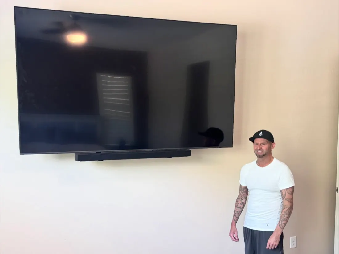 Large TV and soundbar mounted on a bedroom wall